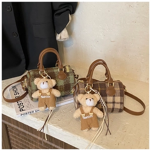 Detail of plaid Boston bag texture with leather straps and plush bear charm