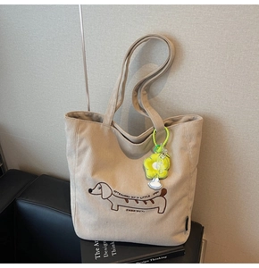Close-up of beige corduroy tote with dachshund embroidery and green flower charm