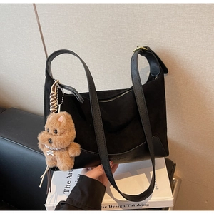 Detail der schwarzen Wildledertasche mit einem süßen Plüschhund-Anhänger am Riemen