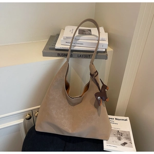 Detail view of khaki suede hobo bag with a cute dark brown puppy charm on a shelf