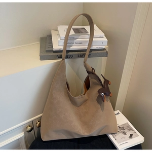 Retro khaki hobo tote bag with a dachshund charm on a minimalist shelf background