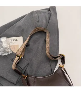 Detail of dark brown leather underarm bag with a wide geometric woven canvas strap