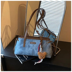 Sac bandoulière bleu texturé avec lanières brunes et détail de breloque ours en peluche