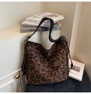 Detail of the leopard print canvas tote bag featuring leather logo and sturdy shoulder strap