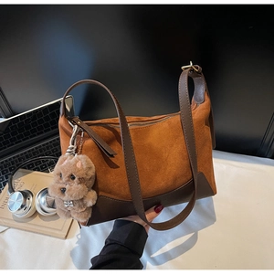 Detail der braunen Wildledertasche mit Top Dog Plüsch-Anhänger in schicker Büro-Umgebung