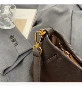 Close-up of vintage brown leather bag with glossy gold-tone metal hook and hardware