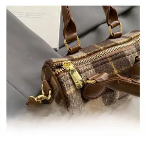Close-up of golden zipper and hardware on a checkered wool boston handbag