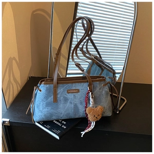 Détail du sac à épaule en jean avec bordure en cuir et charmant ours en peluche marron