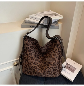 Detail of leopard print canvas tote bag with brown shoulder strap on a bookshelf