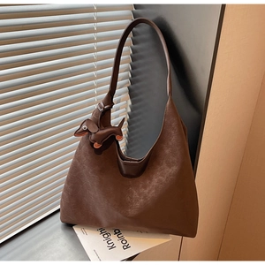 Close-up of brown textured hobo bag with a cute dachshund leather charm attachment