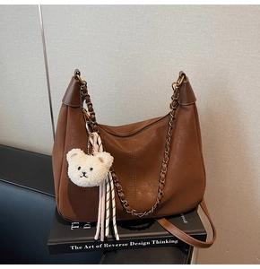 Detail of retro brown hobo bag with bronze chain and white bear plush pendant