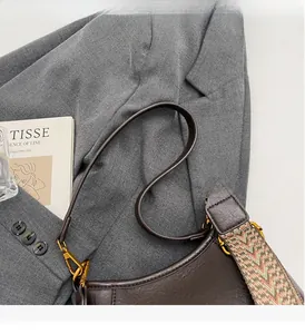 Detail of dark brown vintage leather bucket bag with textured grain and gold metal hardware
