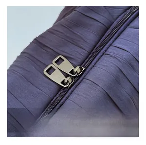 Détail de la double fermeture éclair métallique sur tissu plissé bleu foncé