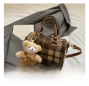 Detail view of mini Boston bag with brown plaid fabric and a cute teddy bear charm