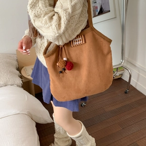 Detailed view of brown canvas tote bag with Bonjour patch and colorful plush charms