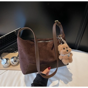 Detail der Wildleder-Patchworktasche mit Plüschbären-Anhänger und Metallreißverschluss