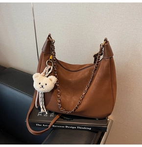 Detailed shot of brown vintage hobo bag with metal chain strap and white plush bear charm