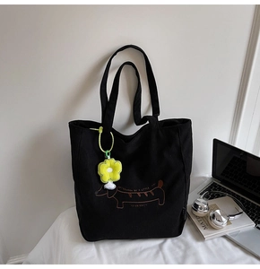 Detail of black corduroy tote bag with dachshund embroidery and yellow sun flower charm