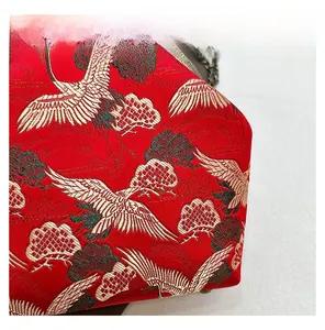 Macro shot of crane embroidery on red vintage crossbody bag with metal kiss-lock frame