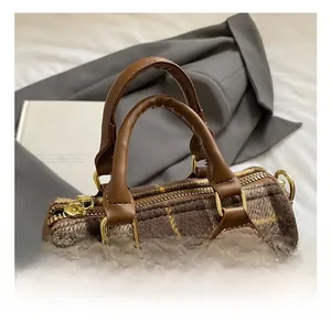 Detail of Boston bag showing brown plaid wool fabric and leather handle with pompom charm