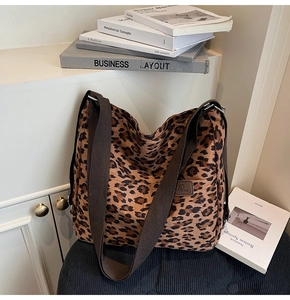 Detail of canvas leopard print tote bag featuring a leather logo patch and wide strap