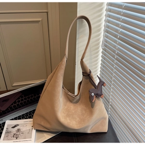 Detail of beige shoulder bag with matte leather texture and cute brown dog charm accessory