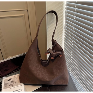 Close-up of a large dark brown matte leather tote bag with a cute dachshund puppy charm