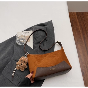 Detail der Wildleder-Patchwork-Tasche mit Plüschwelpen-Anhänger und geprägtem Logo