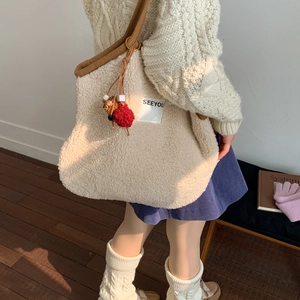 Detail of off-white faux shearling tote bag with brown woven strap and cute charm