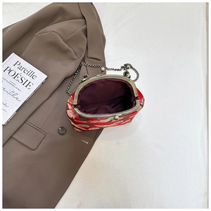 Detail view of red brocade bag featuring elegant crane embroidery and bronze metal clasp