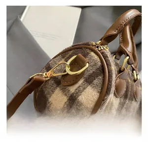 Close-up of golden metal lobster clasp and D-ring on brown plaid Boston handbag