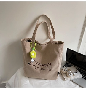 Close-up of beige corduroy tote bag with embroidered dachshund and floral accessory