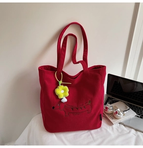 Close-up of red corduroy tote bag with dachshund embroidery and yellow daisy pendant