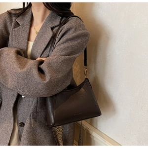 Detail of dark brown vintage shoulder bag featuring triangular stitching and leather texture