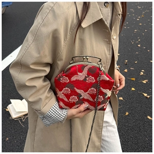 Detailed close-up of crane embroidery on red vintage kiss-lock bag with chain strap