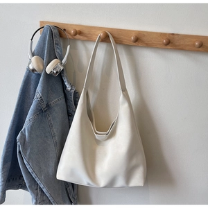 Minimalist cream white hobo bag made of matte PU leather hanging in a casual home setting
