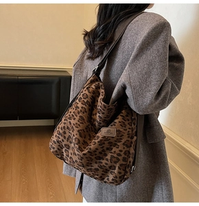 Detail view of large leopard print tote bag with leather logo patch and shoulder strap