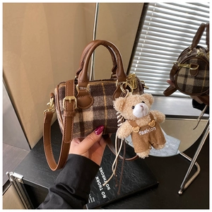 Close-up of mini plaid barrel bag with brown leather trim and a cute teddy bear charm