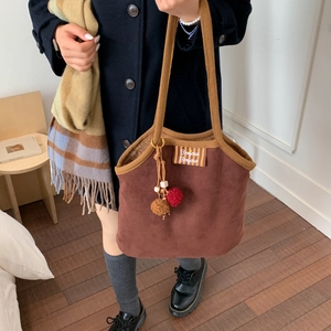 Detail of brown suede tote bag with Bonjour embroidery and plush pom-pom charm