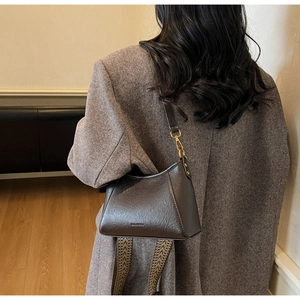 Detail of dark brown vintage faux leather hobo bag with gold buckle and patterned strap