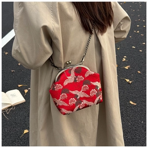 Outdoor shot of a red silk crane embroidery kiss-lock bag with a metal chain strap