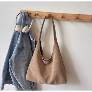 Close-up of matte beige hobo bag hanging on wood hook with lifestyle accessories