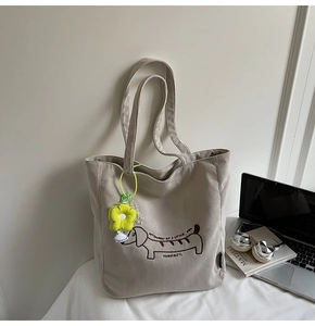 Detailed close-up of corduroy tote bag featuring puppy embroidery and floral charm