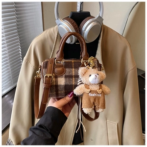Detail showing vintage plaid Boston bag with leather handles and a cute teddy bear charm
