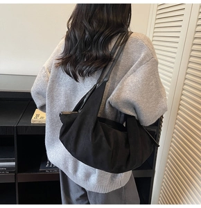 Detail of a large black suede tote bag shown on model in a minimalist home office setting