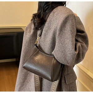 Detail showing the coffee brown vintage shoulder bag with textured leather and wide woven strap