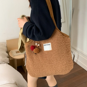 Brown faux shearling underarm bag with SEEYOU label and plush pom-pom charms