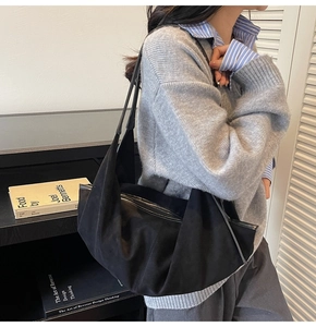 Close-up of black suede tote bag showing natural folds and slim shoulder strap