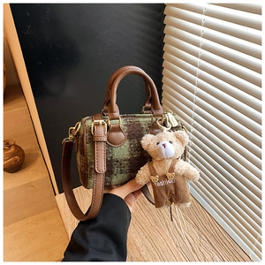 Detail of green plaid boston bag with premium leather handles and a cute bear charm