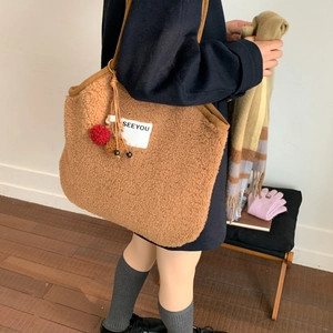 Detail of light brown faux fur shoulder bag with SEEYOU patch and plush ball charms